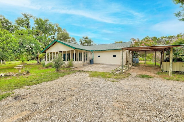 back of property with dirt driveway and a carport