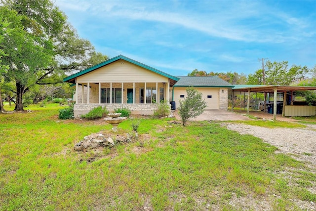 view of front of property featuring driveway, stone siding, a front lawn, and a carport