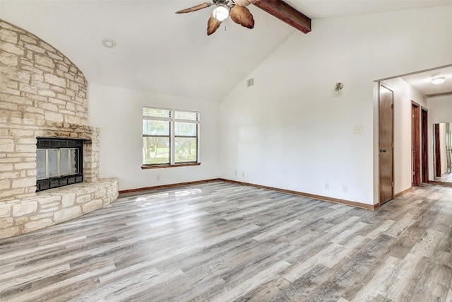 unfurnished living room with a ceiling fan, beamed ceiling, wood finished floors, a fireplace, and high vaulted ceiling