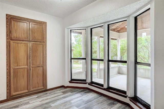 doorway to outside with a textured ceiling and light wood-type flooring