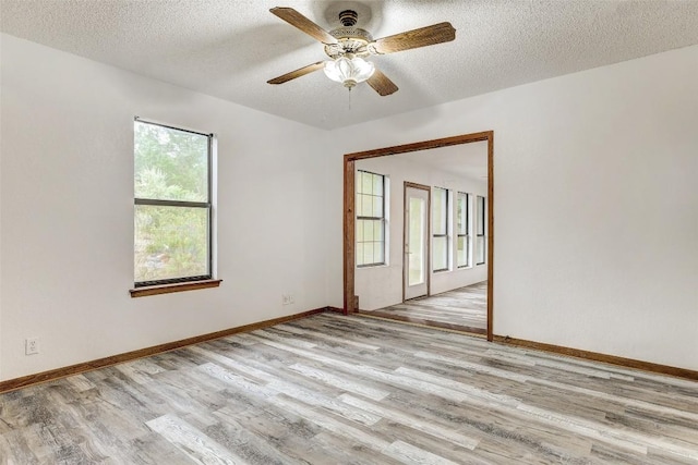 empty room featuring a textured ceiling, wood finished floors, and baseboards