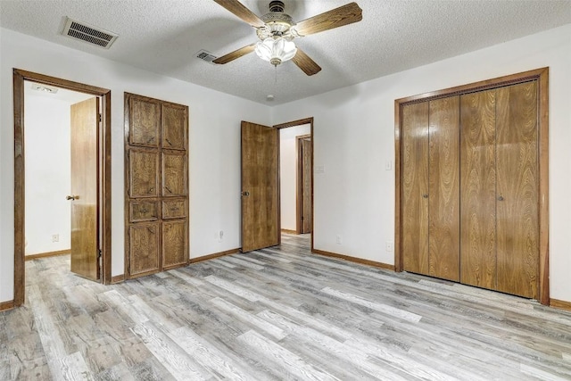 unfurnished bedroom featuring light wood-style floors, visible vents, and a textured ceiling