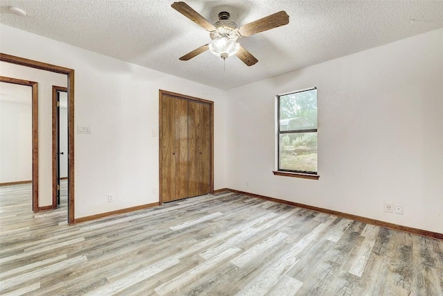 unfurnished bedroom featuring a textured ceiling, a closet, light wood-type flooring, and baseboards