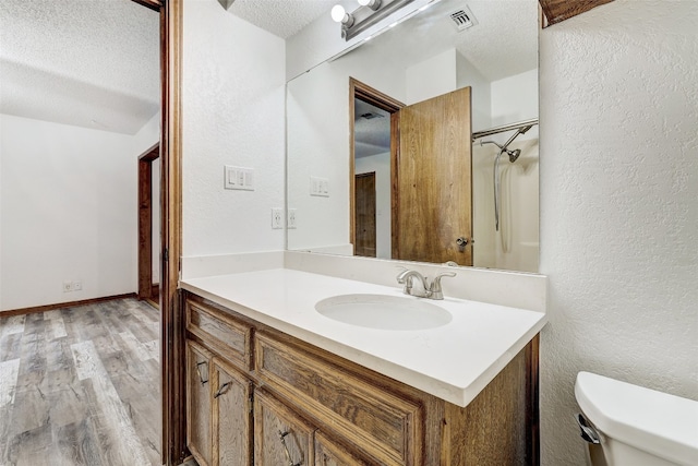 bathroom featuring vanity, a textured ceiling, wood-type flooring, and toilet