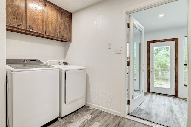 laundry area with light hardwood / wood-style floors, cabinets, and washer and dryer