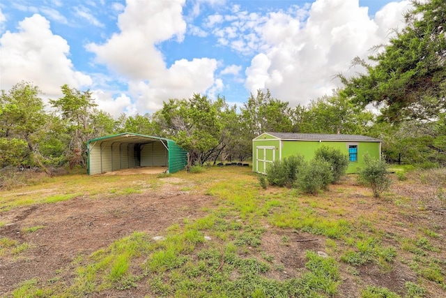 view of yard with a carport, an outdoor structure, and a shed