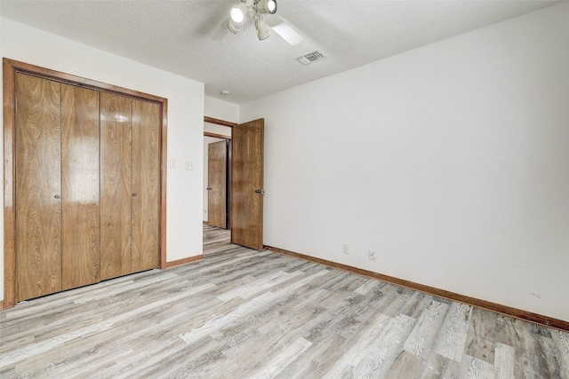 unfurnished bedroom with light hardwood / wood-style floors, a textured ceiling, a closet, and ceiling fan