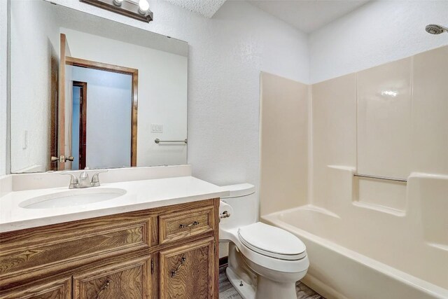 full bathroom featuring washtub / shower combination, toilet, vanity, and a textured ceiling