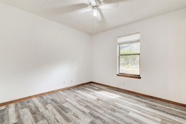 spare room featuring a ceiling fan, a textured ceiling, baseboards, and wood finished floors