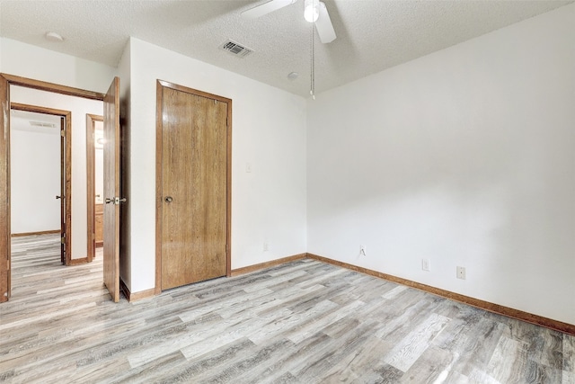 unfurnished bedroom with a closet, a textured ceiling, ceiling fan, and light wood-type flooring