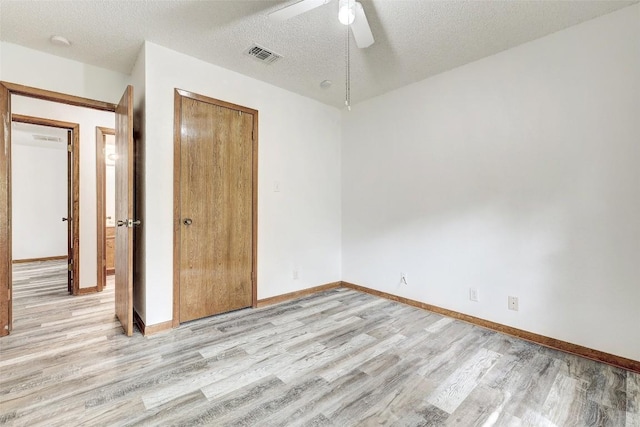 unfurnished bedroom with light wood-style flooring, a textured ceiling, visible vents, and a closet