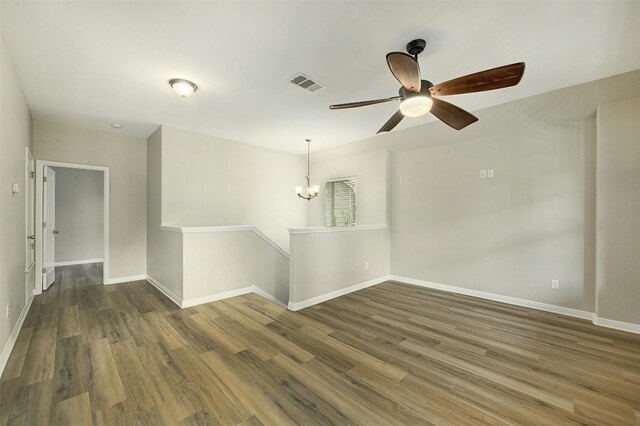 unfurnished room featuring dark wood-type flooring and ceiling fan with notable chandelier