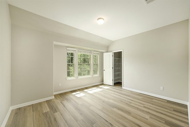 spare room featuring light hardwood / wood-style flooring and vaulted ceiling