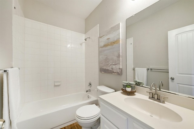 full bathroom featuring tiled shower / bath, vanity, and toilet