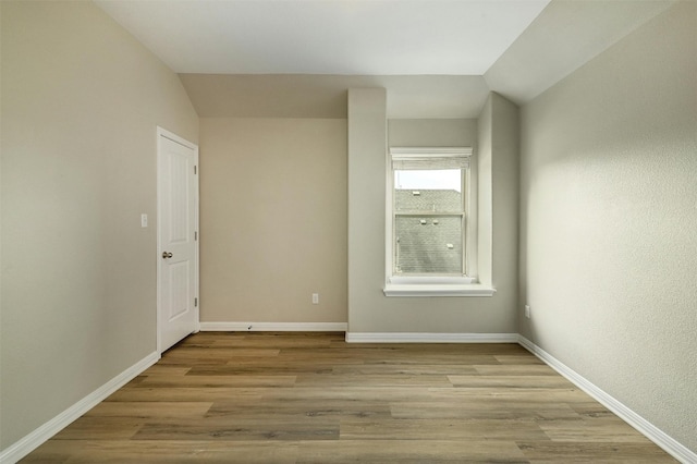 empty room with vaulted ceiling and light wood-type flooring