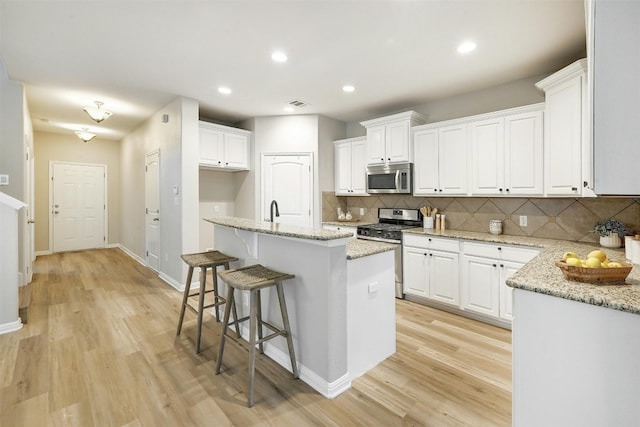 kitchen with appliances with stainless steel finishes, white cabinetry, and a kitchen island