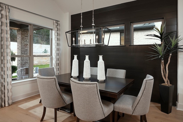 dining room with light hardwood / wood-style flooring, wooden walls, and lofted ceiling