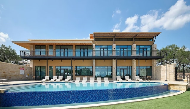 rear view of house with a community pool and a balcony