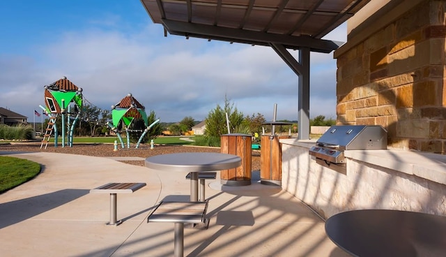 view of patio featuring exterior kitchen and a playground