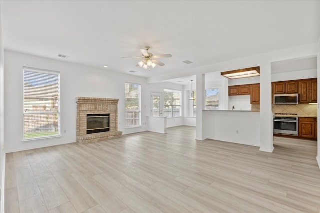 unfurnished living room with a fireplace, light hardwood / wood-style floors, and ceiling fan