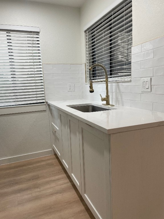 kitchen featuring sink, tasteful backsplash, kitchen peninsula, and light hardwood / wood-style flooring