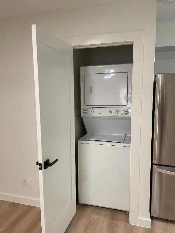 washroom featuring light hardwood / wood-style flooring and stacked washer / dryer