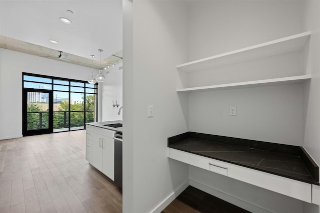 kitchen with pendant lighting, wood-type flooring, white cabinets, and sink