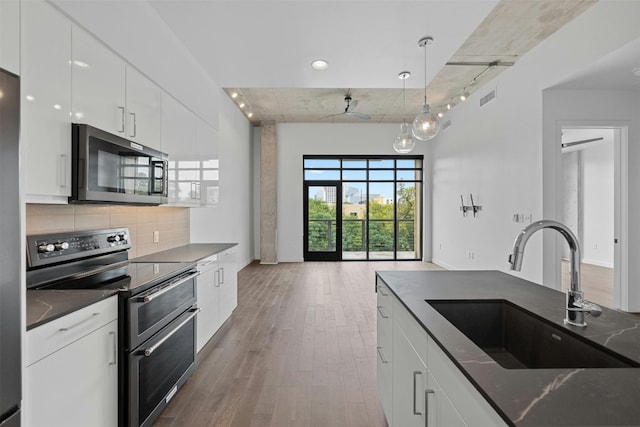 kitchen featuring decorative light fixtures, white cabinetry, stainless steel appliances, hardwood / wood-style floors, and sink