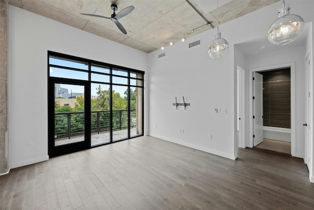 empty room with hardwood / wood-style floors, rail lighting, and ceiling fan