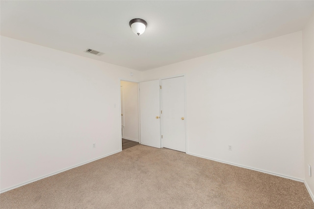 spare room with light colored carpet, visible vents, and baseboards