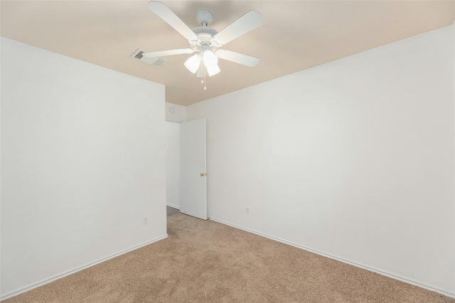 spare room featuring light carpet, ceiling fan, visible vents, and baseboards