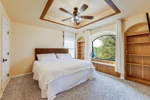 bedroom with carpet flooring, ceiling fan, and a tray ceiling