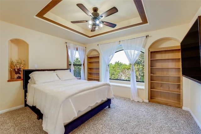 bedroom with light colored carpet, ceiling fan, and a tray ceiling