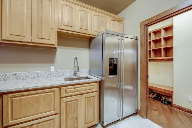 kitchen featuring sink, stainless steel fridge, light stone counters, light hardwood / wood-style floors, and light brown cabinets