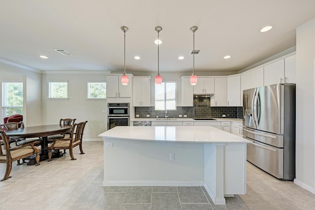 kitchen with a kitchen island, sink, white cabinets, hanging light fixtures, and stainless steel appliances