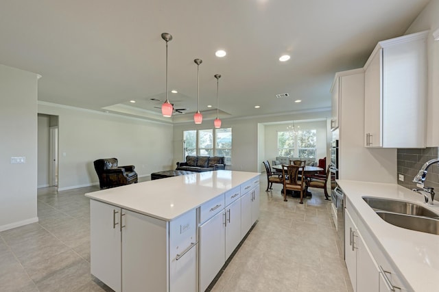 kitchen featuring pendant lighting, sink, crown molding, white cabinetry, and a kitchen island