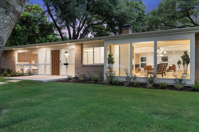 view of front of home with a front yard, brick siding, and a chimney