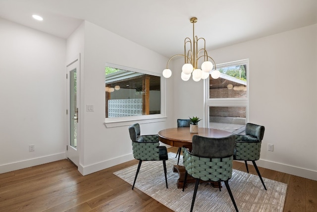 dining room featuring wood-type flooring, a notable chandelier, and baseboards