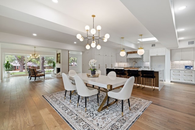 dining room with light wood finished floors, visible vents, a chandelier, and recessed lighting