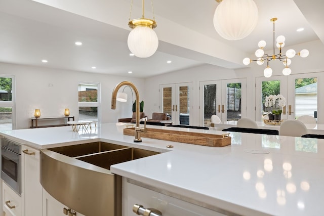 kitchen featuring hanging light fixtures, light countertops, french doors, a healthy amount of sunlight, and a sink