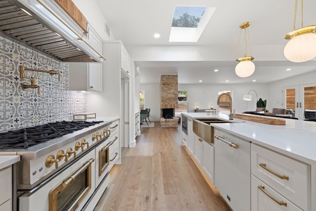 kitchen featuring a skylight, premium range hood, light countertops, double oven range, and a sink