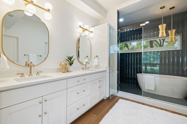 full bathroom featuring double vanity, wood finished floors, a sink, and visible vents