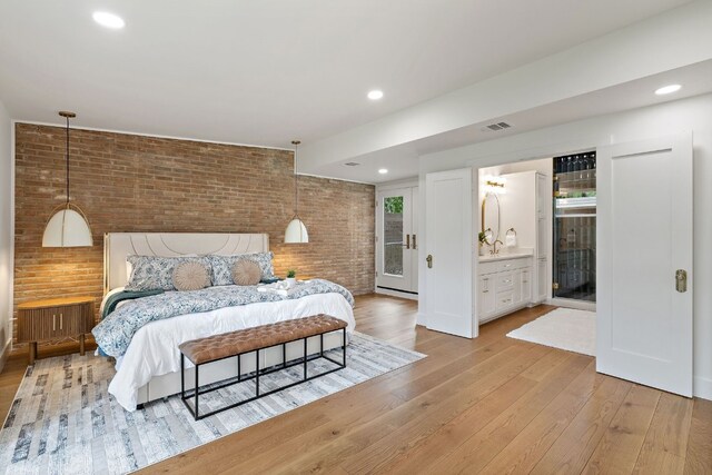 bedroom featuring ensuite bathroom, recessed lighting, brick wall, visible vents, and light wood-style floors