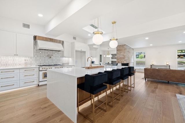 kitchen featuring visible vents, high end white range, light countertops, backsplash, and light wood finished floors