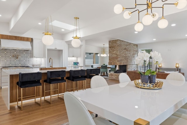 dining space featuring a notable chandelier, recessed lighting, a fireplace, and light wood-style floors