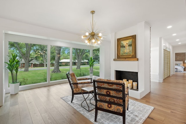 dining area featuring light wood finished floors, a fireplace, a notable chandelier, and recessed lighting