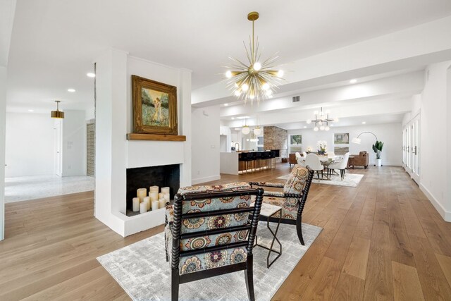 dining room with baseboards, light wood-type flooring, a multi sided fireplace, a notable chandelier, and recessed lighting