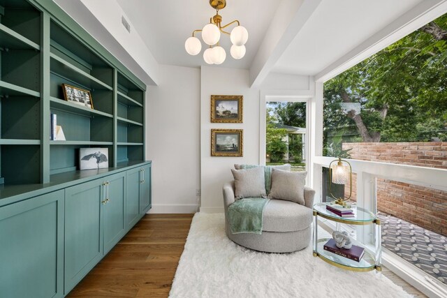 living area with a chandelier, beamed ceiling, dark wood finished floors, and baseboards