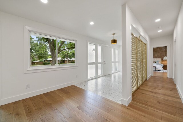 hallway featuring light wood-style floors, baseboards, and recessed lighting