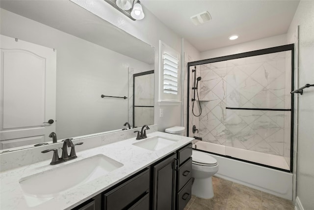 full bathroom with tile patterned floors, bath / shower combo with glass door, toilet, and double sink vanity